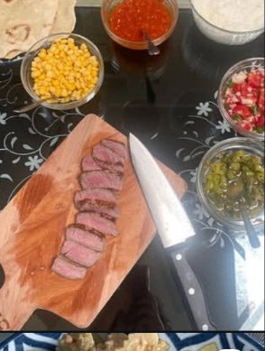 Sliced sirloin and taco fixings prepped on a board