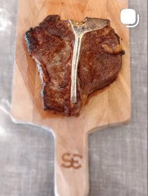 Dry-aged T-bone steak rested on a wooden board