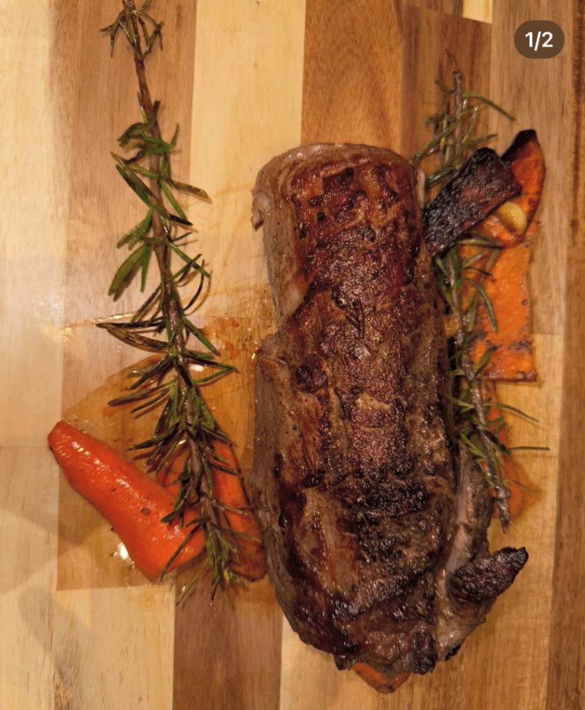 Seared steak on a wooden board with rosemary and roasted carrots