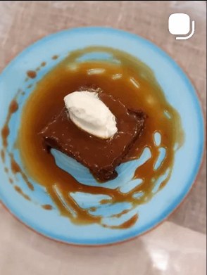 Sticky toffee pudding with cream on a turquoise plate