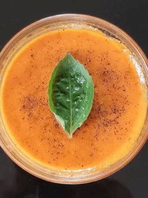 Creamy tomato basil soup with a fresh basil leaf