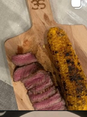 Grilled steak with charred corn on a wooden board