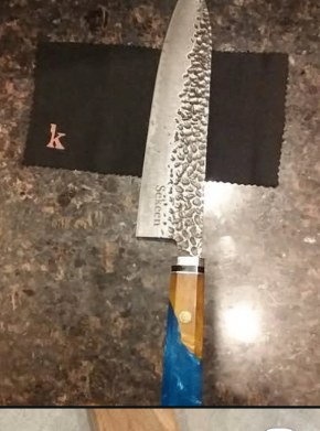 Hand-forged Japanese chef knife resting on stone