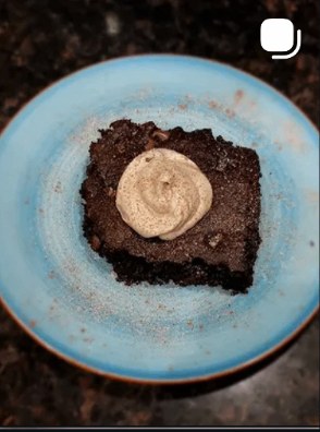 Chocolate brownie with cinnamon cream on a blue plate