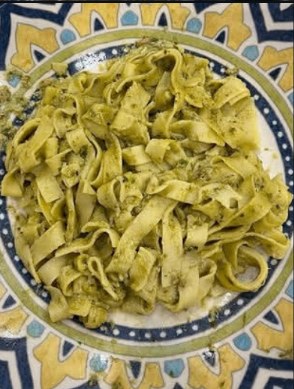 Homemade pesto tagliatelle plated on a patterned blue dish