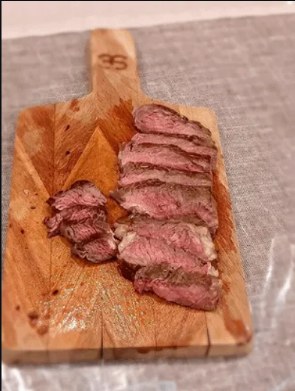 Sliced sirloin fanned out on a hand-cut wood board